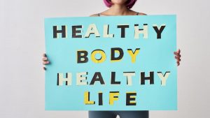 A woman holds a motivational poster advocating a healthy body and life for wellness.